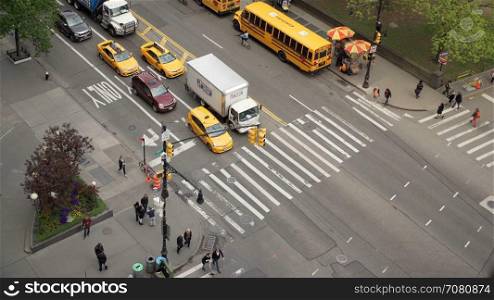 Aerial view of people move across crosswalk of city intersection