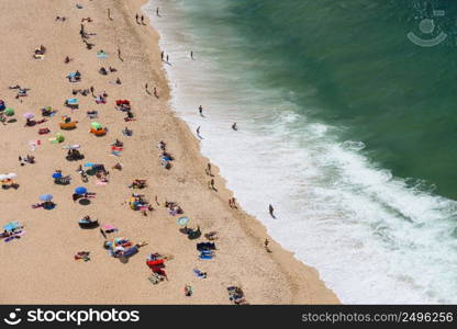 Aerial view of people sunbathing on the ocean beach at hot summer day