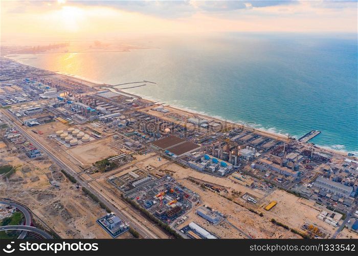 Aerial view of petrochemical oil refinery and sea in industrial engineering and energy concept in Dubai, urban city, UAE. Oil and gas tanks pipelines in industry. Modern metal factory. Power plant.