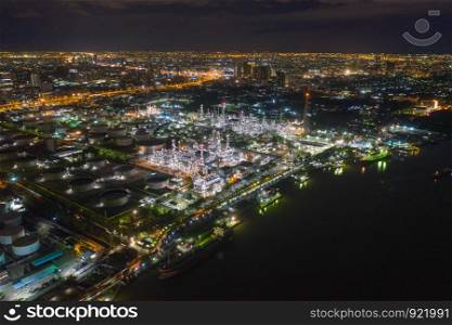 Aerial view of petrochemical oil refinery and sea in industrial engineering concept in Bangna district at night, Bangkok City, Thailand. Oil and gas tanks pipelines in industry. Modern metal factory.