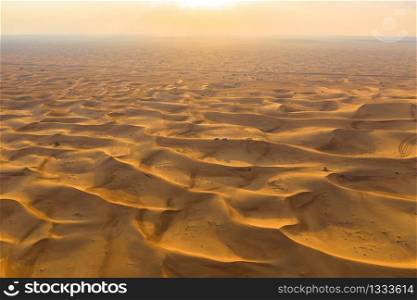 Aerial view of red Desert Safari with sand dune in Dubai City, United Arab Emirates or UAE. Natural landscape background at sunset time. Famous tourist attraction. Pattern texture of sand. Top view.