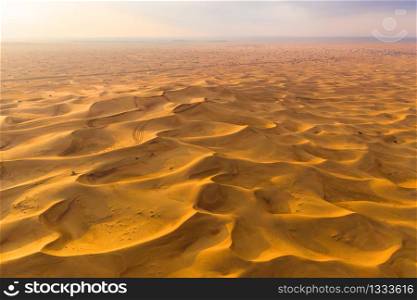 Aerial view of red Desert Safari with sand dune in Dubai City, United Arab Emirates or UAE. Natural landscape background at sunset time. Famous tourist attraction. Pattern texture of sand. Top view.