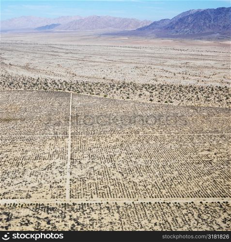 Aerial view of remote California desert with grid pattern and mountain range in background.