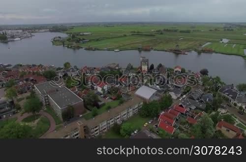 Aerial view of river flowing through the township with windmills and green fields, Netherlands