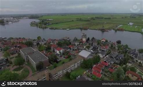 Aerial view of river flowing through the township with windmills and green fields, Netherlands
