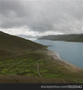 Aerial view of road passing through agricultural fields along Yamdrok Lake, Nagarze, Shannan, Tibet, China