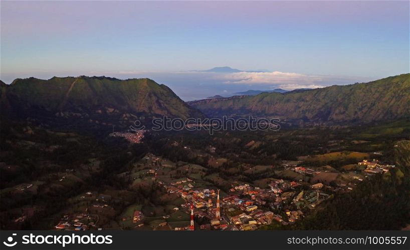 Aerial view of rock cliff at Kawah Ijen volcano with forest and fog cloud at sunrise. Panoramic view at East Java, Indonesia. Natural landscape background.