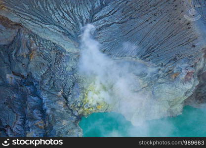 Aerial view of rock cliff at Kawah Ijen volcano with turquoise sulfur water lake at sunrise. Panoramic view at East Java, Indonesia. Natural landscape background.