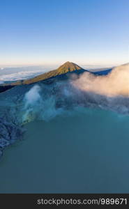 Aerial view of rock cliff at Kawah Ijen volcano with turquoise sulfur water lake at sunrise. Panoramic view at East Java, Indonesia. Natural landscape background.