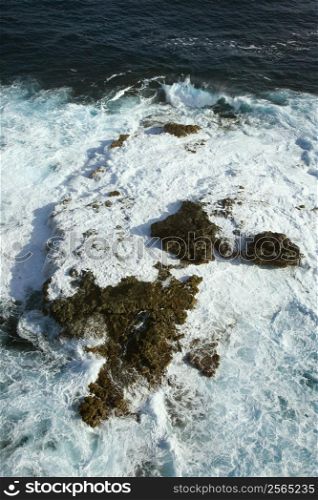 Aerial view of rocks in Pacific ocean with water swirling around them off the coast of Maui, Hawaii.