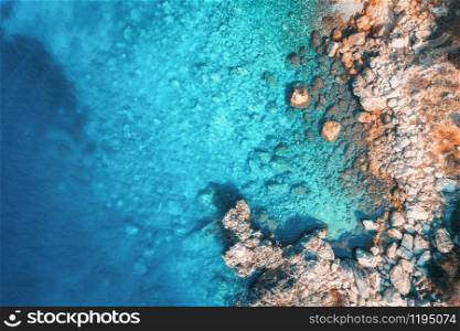 Aerial view of rocky beach and sea with transparent blue water at sunset. Coast of adriatic sea at sunset in summer. Top view. Landscape with clear azure water, stones and rocks. Nature background