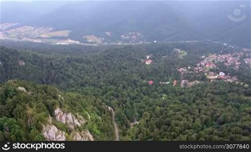 Aerial view of Romania mountains landscape town valley scenery in summer day. 4K aerial motion over forest and trees.