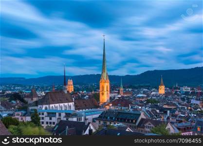 Aerial view of roofs and church towers in Old Town of Zurich, the largest city in Switzerland, during evening blue hour.. Zurich, the largest city in Switzerland