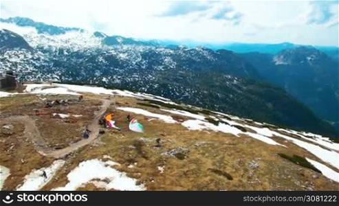 Aerial view of running paraglider with write color parachute on the mountainside. Austria, Obertraun