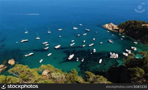 Aerial view of sailing boat and yachts parked at the wild harbor near the coast in Spain, Catalonia