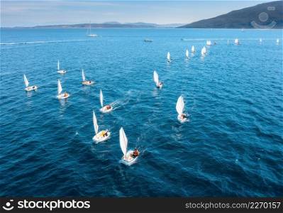 Aerial view of sailing competition in summer. Top view of sail boats, blue sea at sunrise. Yachting in Lefkada island, Greece. Tropical landscape with floating yachts and boats. Sport and extreme