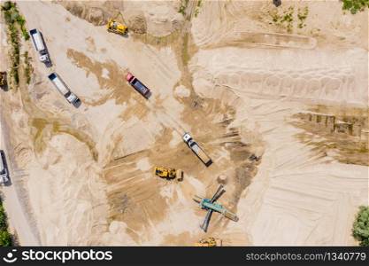 Aerial view of sand quarry with trucks and bulldozers. Heavy bulldozer loading sand,
