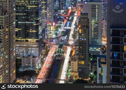Aerial view of Sathorn intersection or junction with cars traffic, Bangkok Downtown. Thailand. Financial district in smart urban city and technology. Skyscraper office buildings at night