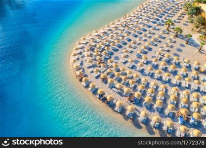 Aerial view of sea, empty sandy beach with sun beds and umbrellas at sunset in summer. Blue lagoon in Oludeniz, Turkey. Tropical landscape with clear turquoise water, deck chair. Travel and leisure