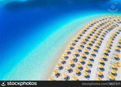 Aerial view of sea, empty sandy beach with sun beds and umbrellas at sunny day in summer. Blue lagoon in Oludeniz, Turkey. Tropical landscape with clear turquoise water, deck chair. Travel and nature