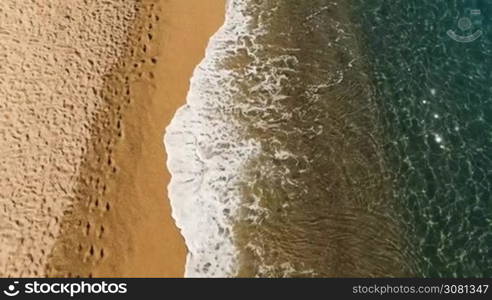 Aerial view of sea waves of reaching shore with yellow sandy. Spain, Catalonia