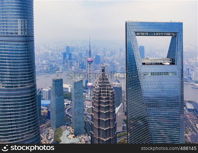 Aerial view of Shanghai Downtown, China. Financial district and business centers in smart city in Asia. Top view of skyscraper and high-rise office buildings at sunset.