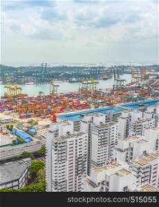 Aerial view of Singapore cargo shipping port with freight cranes and transportational containers, urban area with modern buildings in foreground