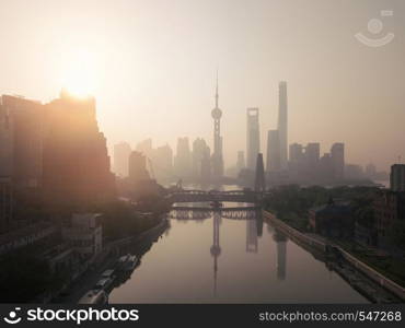 Aerial view of skyscraper and high-rise office buildings in Shanghai Downtown with fog, China. Financial district and business centers in smart city in Asia at sunrise.