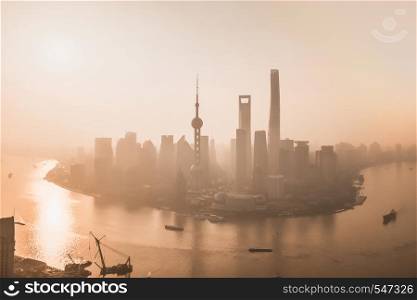 Aerial view of skyscraper and high-rise office buildings in Shanghai Downtown with fog, China. Financial district and business centers in smart city in Asia at sunrise.