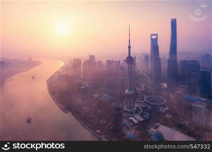 Aerial view of skyscraper and high-rise office buildings in Shanghai Downtown with fog, China. Financial district and business centers in smart city in Asia at sunrise.