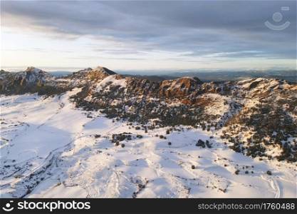 Aerial view of snow covered mountains at sunset in Obarenes mountain range, Burgos province, Spain. High quality photo. Aerial view of snow covered mountains at sunset in Obarenes mountain range, Burgos province, Spain.