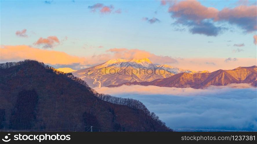 Aerial view of snowy mountain hills with morning mist or fog at sunrise in Nagano City, Japan. Nature landscape background.