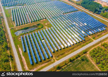 Aerial view of solar panels or solar cells on the roof in farm. Power plant with green field, renewable energy source in Thailand. Eco technology for electric power in industry.