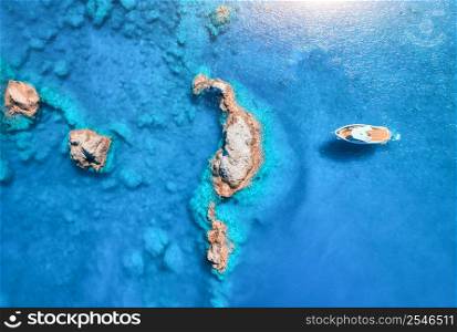 Aerial view of speed boat on blue sea at sunset in summer. Motorboat on sea bay, rocks in clear turquoise water. Tropical landscape with yacht, stones. Top view from drone. Travel in Oludeniz, Turkey