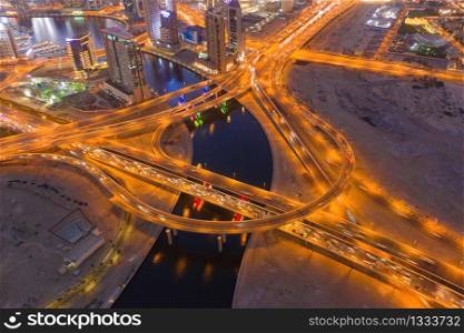 Aerial view of street on highway junctions. Bridge roads shape circle in structure of transportation concept. Top view. Urban city, Dubai at night, UAE. Architecture landscape background.