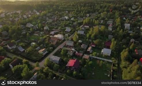 Aerial view of summer houses or village among the green forests at sunset, Russia