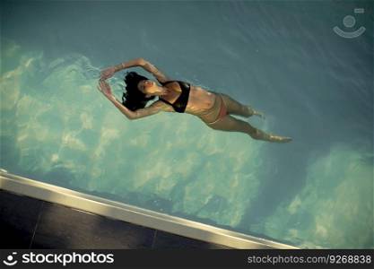 Aerial view of swimming woman floating in swimming pool at summer day