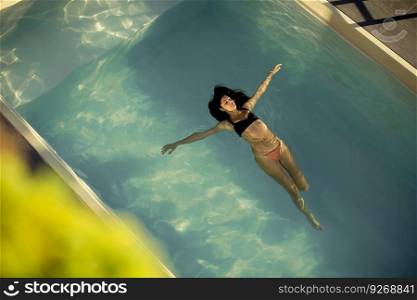 Aerial view of swimming woman floating in swimming pool at summer day
