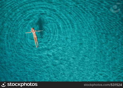 Aerial view of swimming woman in Blue Lagoon. Mediterranean sea in Oludeniz, Turkey. Summer seascape with girl, clear azure water, waves at sunrise. Transparent water.Top view from flying drone.Travel. Aerial view of swimming woman in mediterranean sea