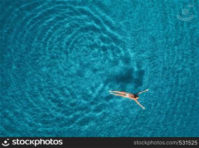Aerial view of swimming woman in Blue Lagoon. Mediterranean sea in Oludeniz, Turkey. Summer seascape with girl, clear azure water, waves in sunny day. Transparent water. Top view from flying drone. Aerial view of swimming woman in mediterranean sea