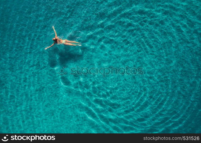 Aerial view of swimming woman in Blue Lagoon. Mediterranean sea in Oludeniz, Turkey. Summer seascape with girl, clear azure water, waves in sunny day. Transparent water. Top view from flying drone. Aerial view of swimming woman in mediterranean sea