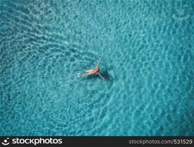 Aerial view of swimming woman in Blue Lagoon. Mediterranean sea in Oludeniz, Turkey. Summer seascape with girl, clear azure water, waves at sunrise. Transparent water.Top view from flying drone.Travel. Aerial view of swimming woman in mediterranean sea