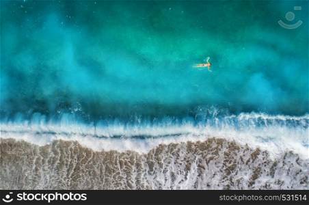 Aerial view of swimming woman in mediterranean sea in Oludeniz, Turkey. Beautiful summer seascape with girl, clear azure water, waves and sandy beach in sunny day. Top view from flying drone. Nature. Aerial view of swimming woman in mediterranean sea