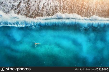Aerial view of swimming woman in mediterranean sea in Oludeniz, Turkey. Beautiful summer seascape with young girl, blue water, waves and sandy beach at sunset. Top view from flying drone. Holiday. Aerial view of swimming woman in mediterranean sea