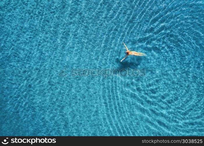 Aerial view of swimming woman in the sea at sunset in Maldives. Aerial seascape with young girl, clear blue water, waves in summer. Transparent water. Top view. Resort on seashore. Holiday. Aerial view of swimming woman in mediterranean sea. Aerial view of swimming woman in the sea at sunset in Maldives