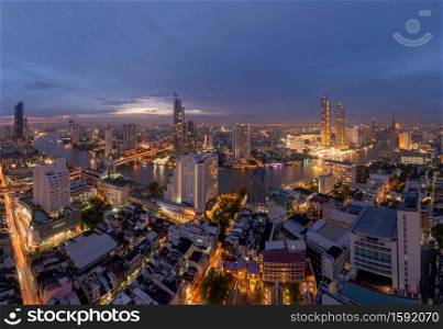 Aerial view of Taksin Bridge with Chao Phraya River, Bangkok Downtown. Thailand. Financial district and business centers in smart urban city. Skyscraper and high-rise buildings at night