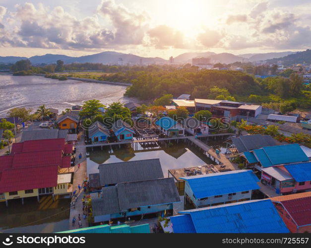 Aerial view of Thai traditional Asian fishing village near sea beach. Floating houses at sunset background in rural area, Phuket island. Thailand. Top view