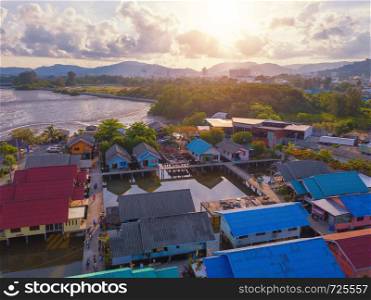 Aerial view of Thai traditional Asian fishing village near sea beach. Floating houses at sunset background in rural area, Phuket island. Thailand. Top view