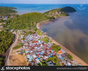 Aerial view of Thai traditional Asian fishing village with boats on sea beach. Residential houses at noon background in rural area, Phuket island. Thailand. Top view