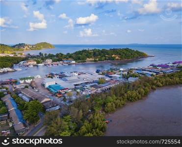 Aerial view of Thai traditional Asian fishing village with boats on sea beach. Residential houses at noon background in rural area, Phuket island. Thailand. Top view